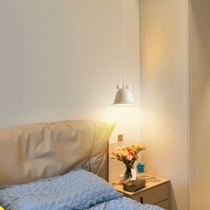 Carins pendant light above nightstand in bedroom. Bell-shaped.