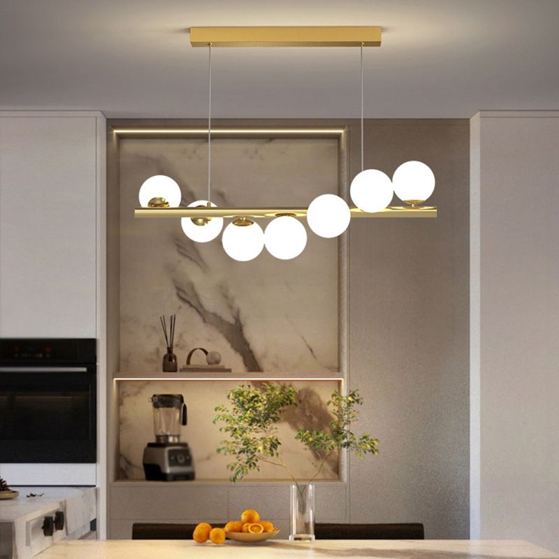 Gold pendant light over a kitchen island with white globe lights.