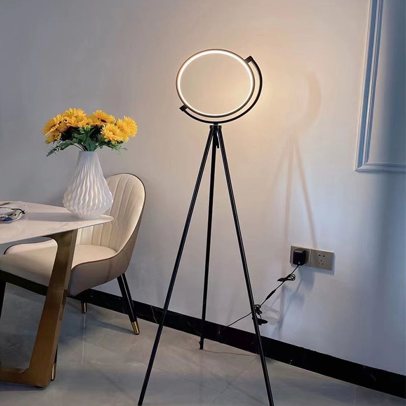 Modern metal tripod floor lamp illuminating living room