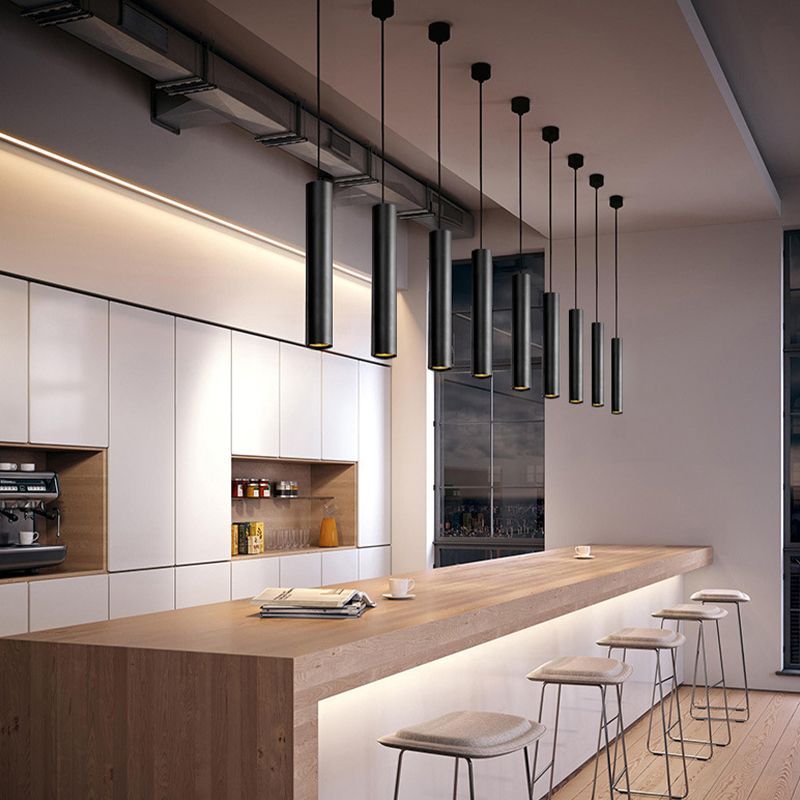 Black cylinder pendant lights above a bar counter