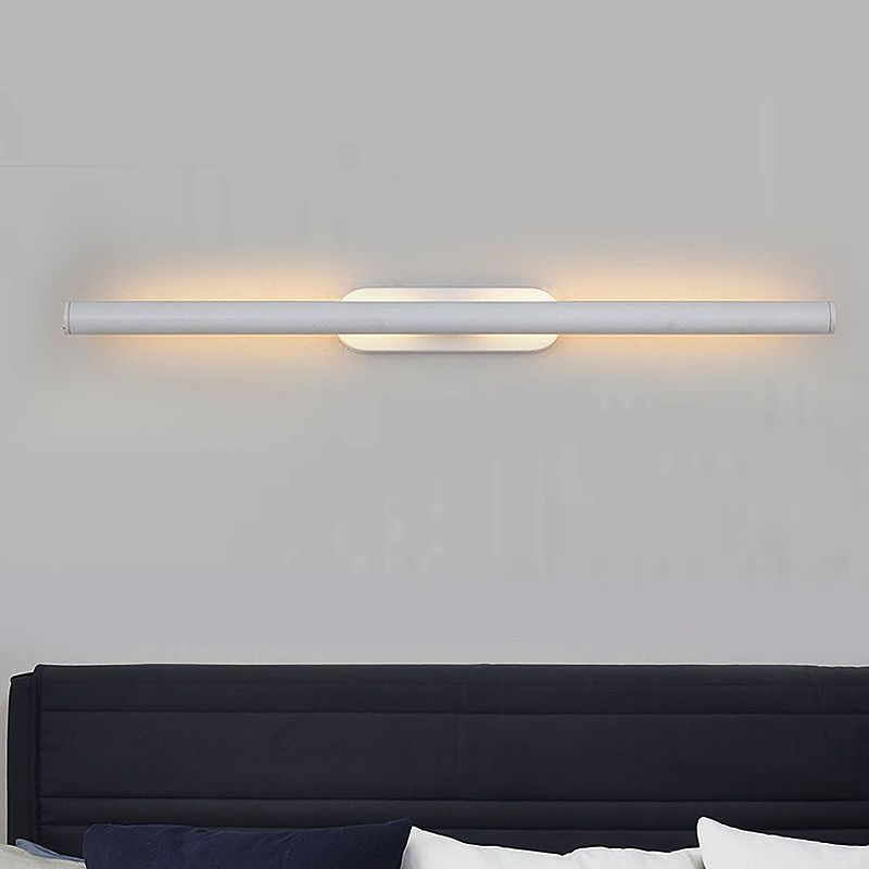 White minimalist tube wall lamp installed above bed