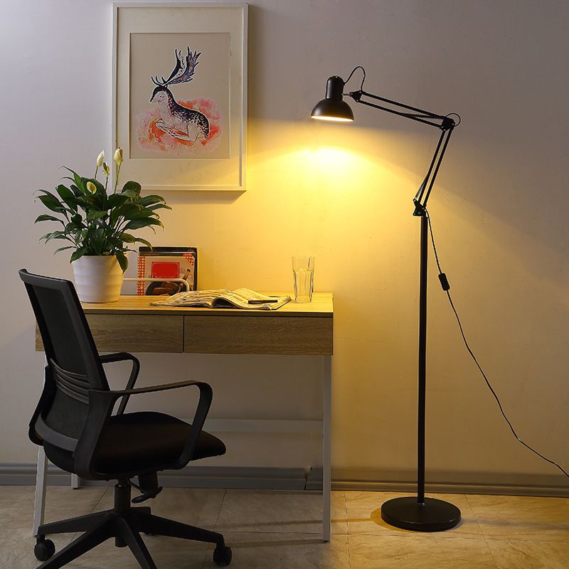 Modern black floor lamp illuminating a desk in bedroom