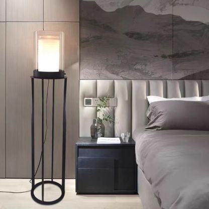 Eryn cylinder floor lamp, glass shade, metal frame in bedroom setting.