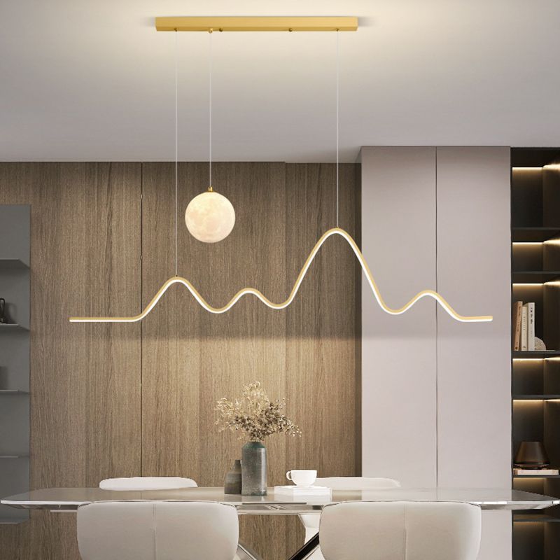 Gold Louise wavy pendant light above dining table.