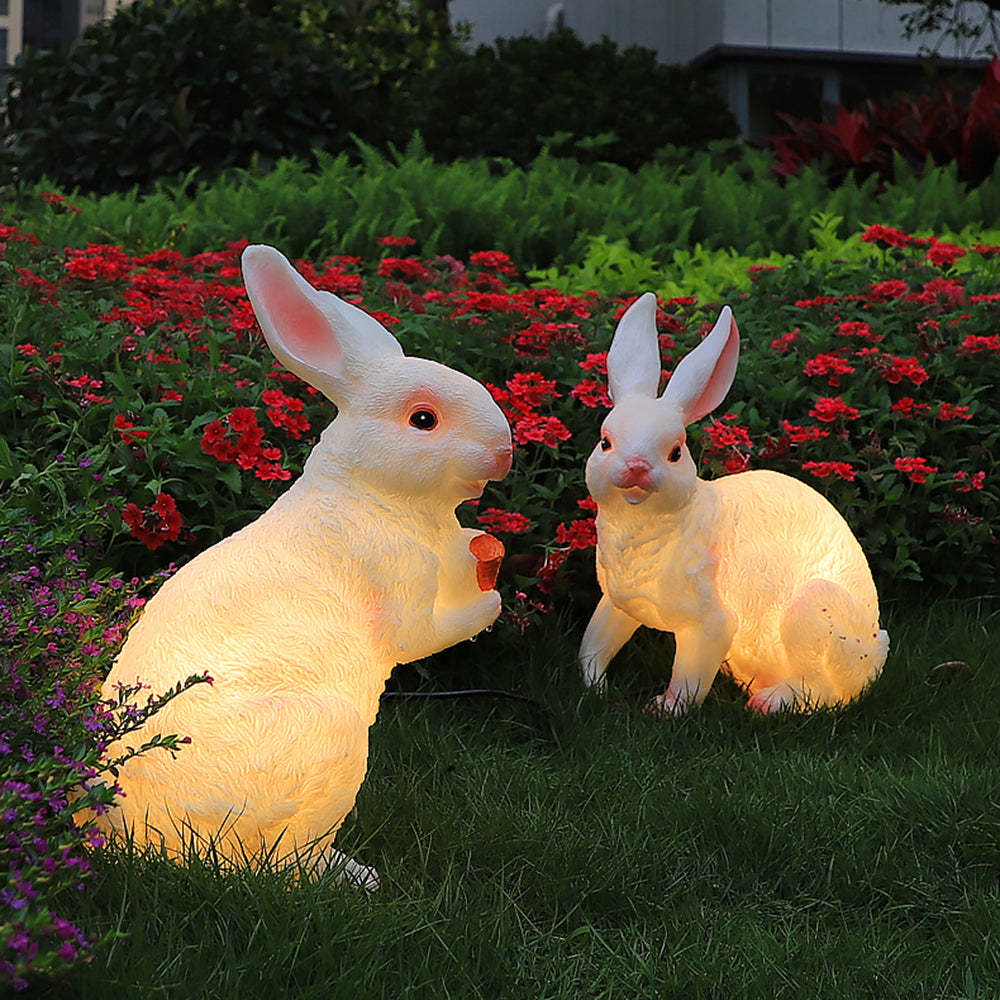 Two rabbit outdoor floor lamps in a garden setting.