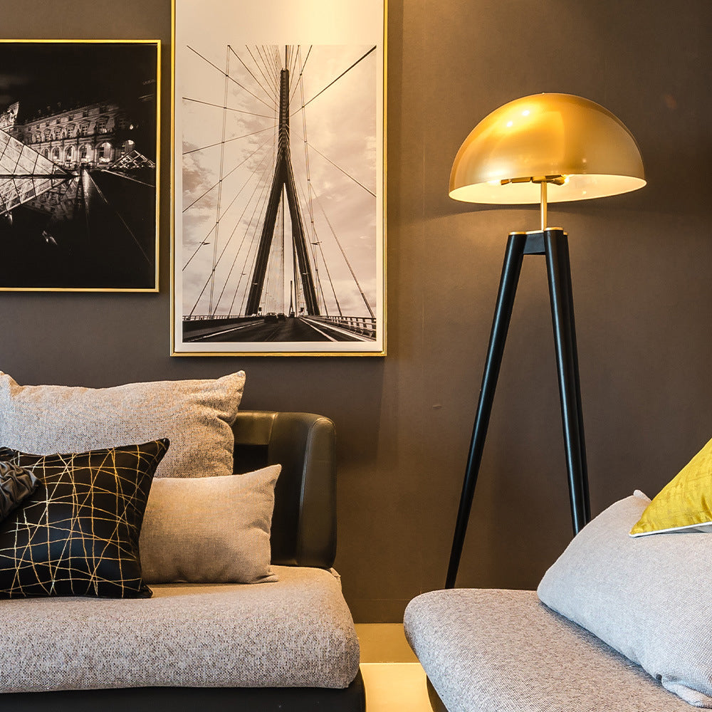 Carins metal tripod floor lamp with gold shade in living room.