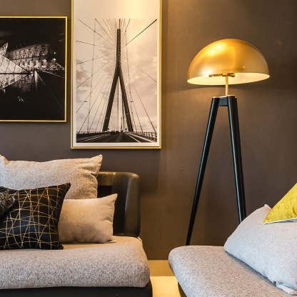 Carins metal tripod floor lamp with gold shade in living room.