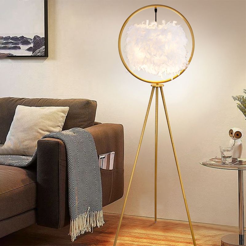 Gold tripod floor lamp with feather shade in a living room