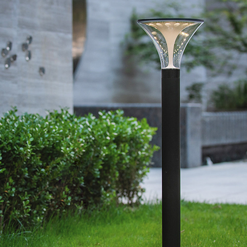 Modern metal outdoor path light illuminating a garden