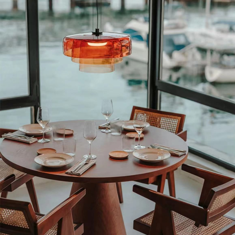 Orange Morandi pendant light over dining table with a view of boats