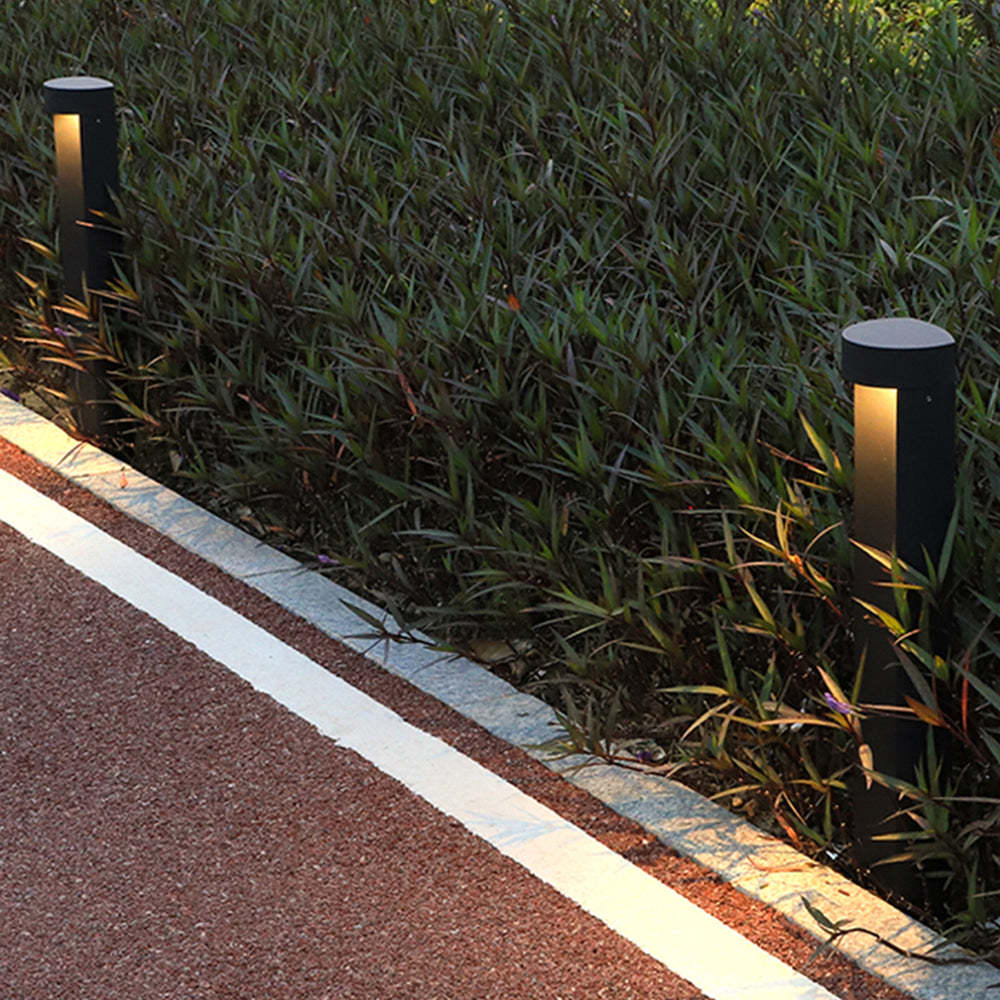 Modern cylindrical outdoor path lights illuminating pathway