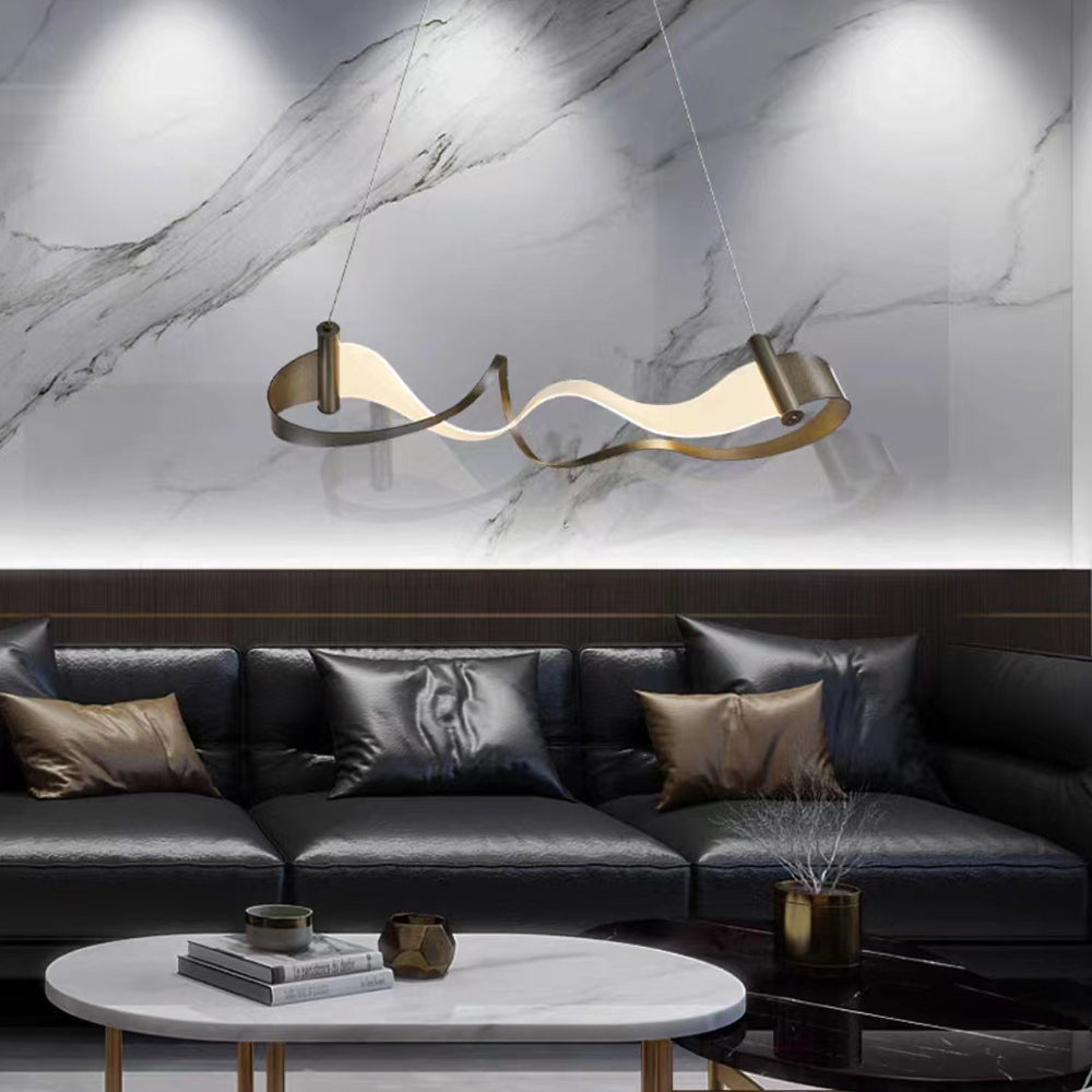 Modern wavy metal pendant light above black leather sofa.