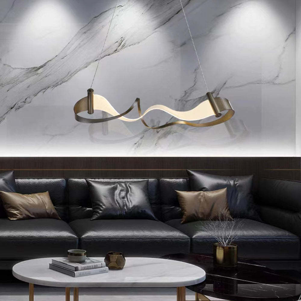 Modern wavy metal pendant light above black leather sofa.