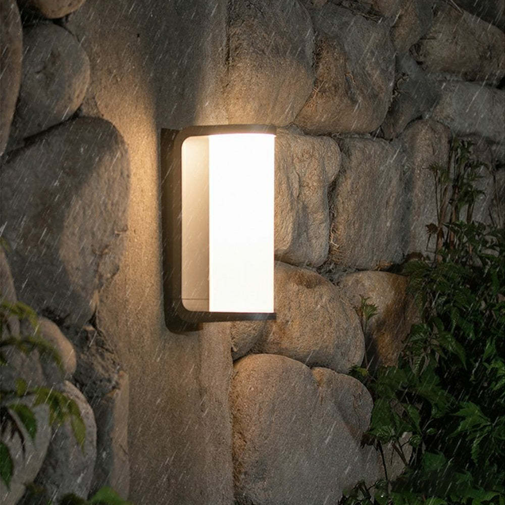Orr modern outdoor wall lamp on stone wall in rain. Cylindrical metal lighting.