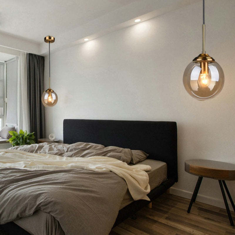 Amber glass pendant light over a bed in a bedroom