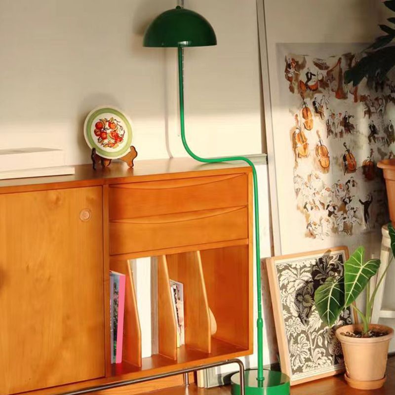 Green Salgado Floor Lamp next to a mid-century style wooden cabinet