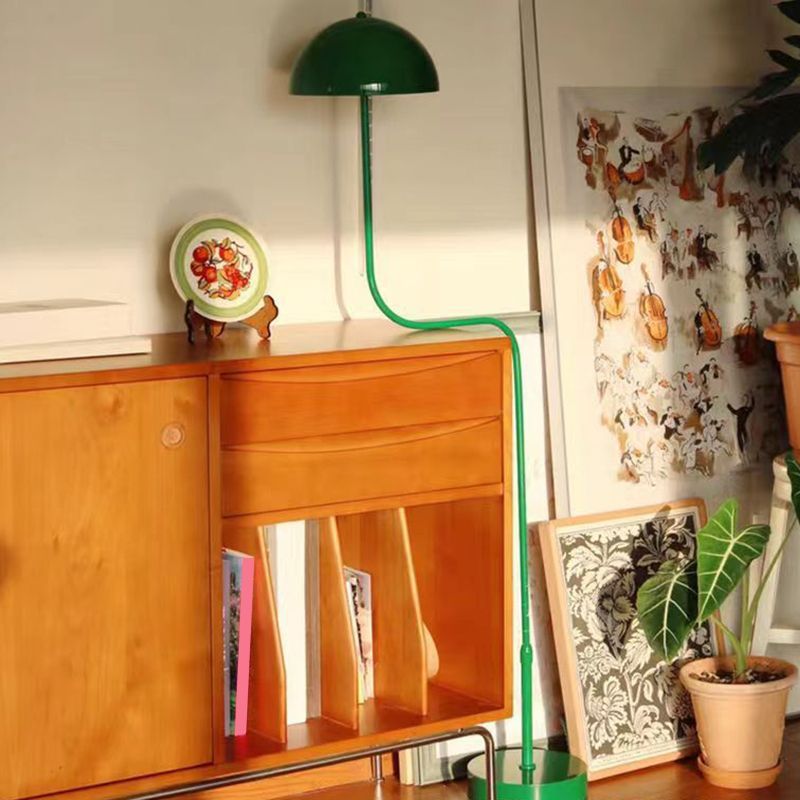 Green Salgado Floor Lamp next to a mid-century style wooden cabinet