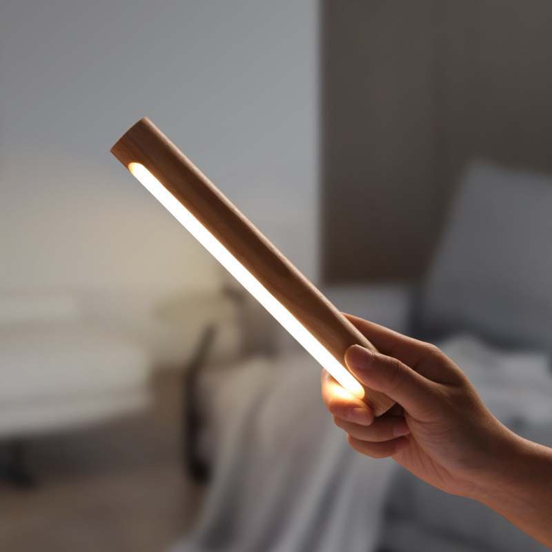 Ozawa wood wall lamp held in hand, lit.