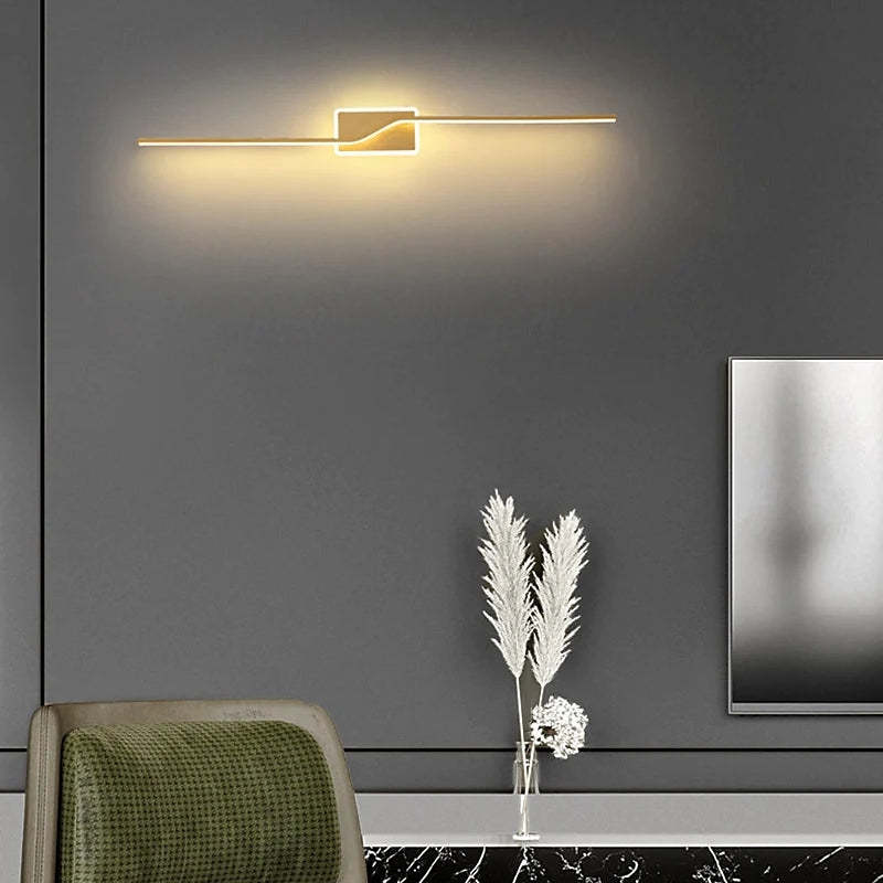 Modern minimalist wall lamp with gold finish in a living room.