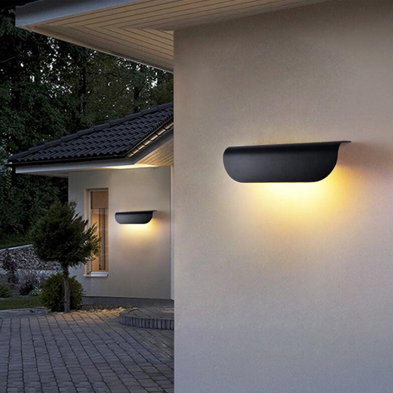 Modern black outdoor wall lamp illuminating a garden