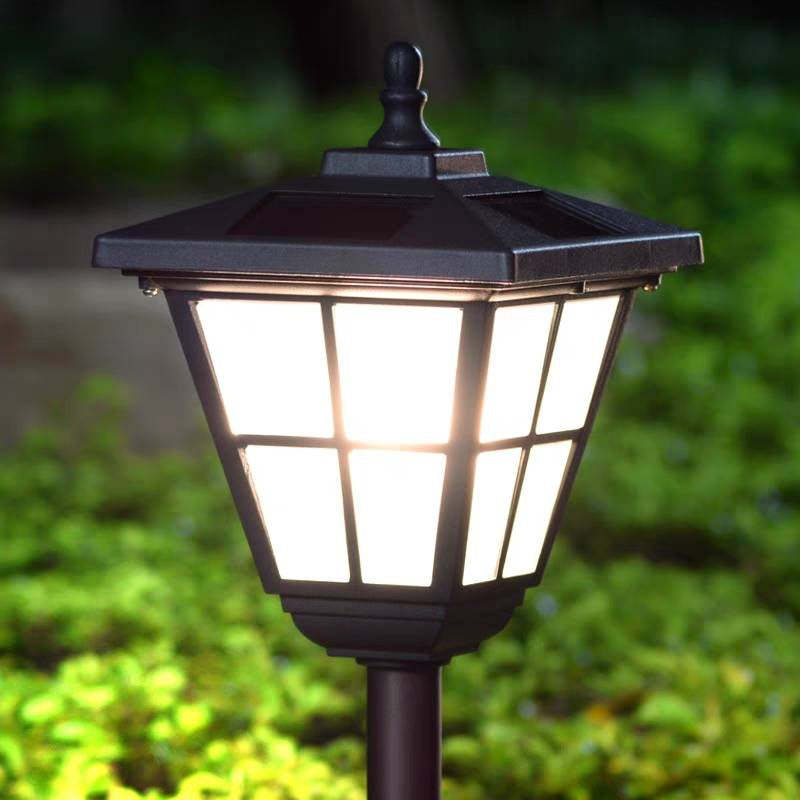 Pena Modern Solar Bollard Light glowing in garden