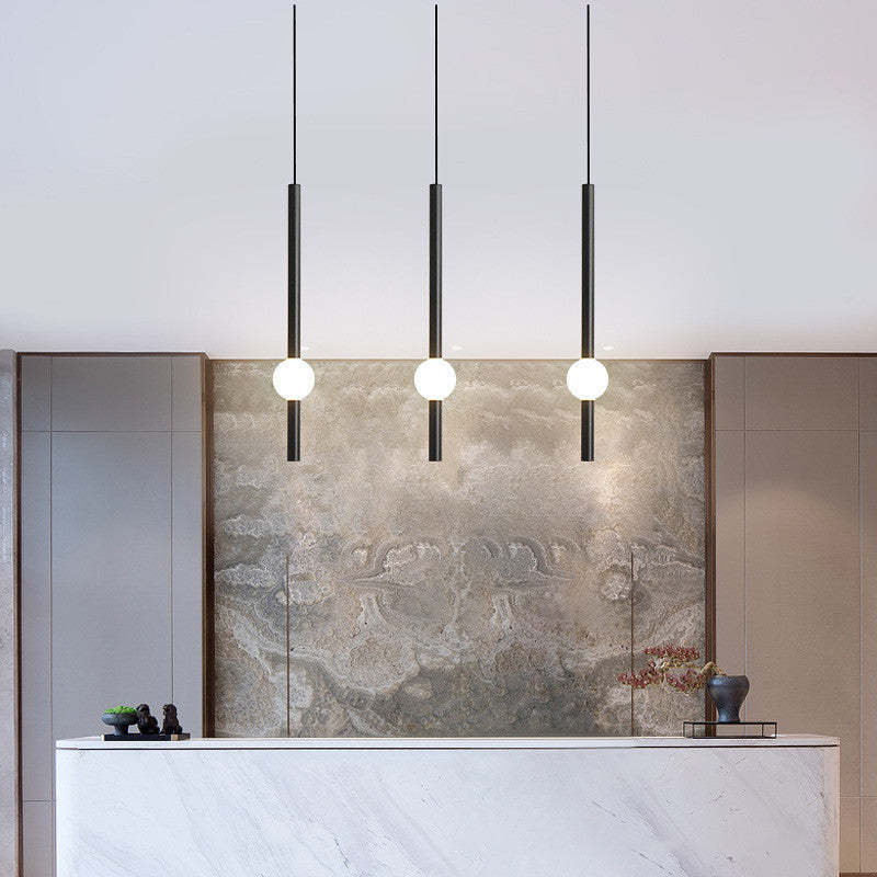 Carr minimalist linear globe pendant lights above counter.