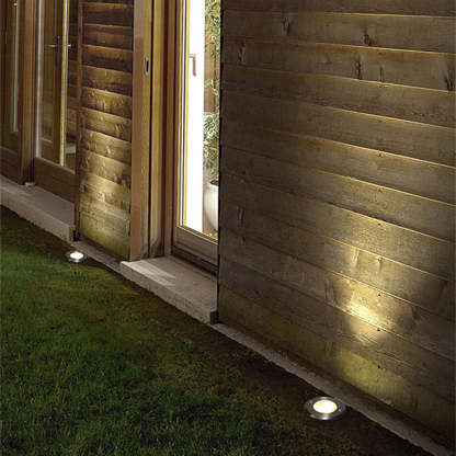 Pena metal outdoor step light illuminates wooden patio.