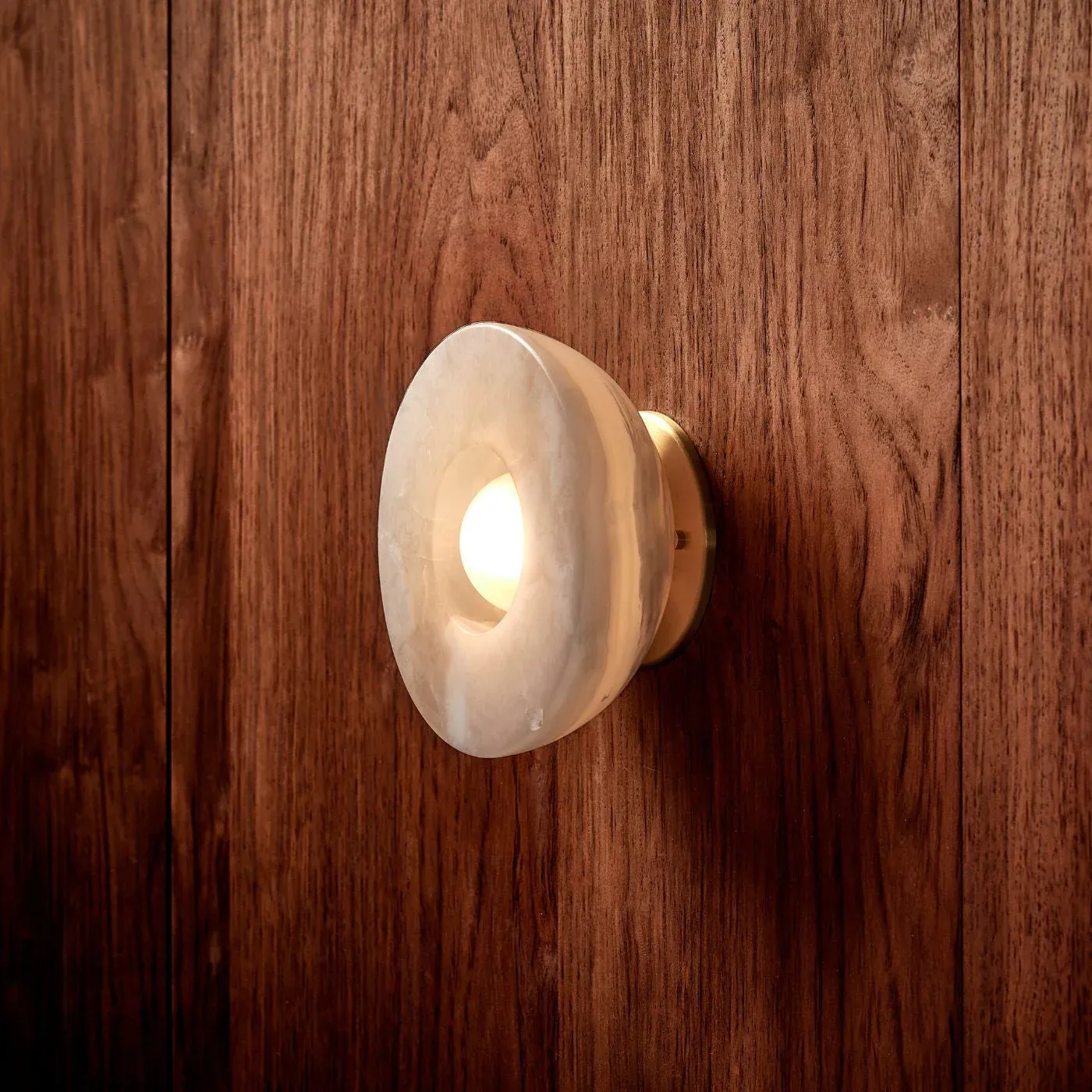 Elif Marble Wall Lamp illuminated on wood, Lassola