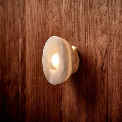 Elif Marble Wall Lamp illuminated on wood, Lassola
