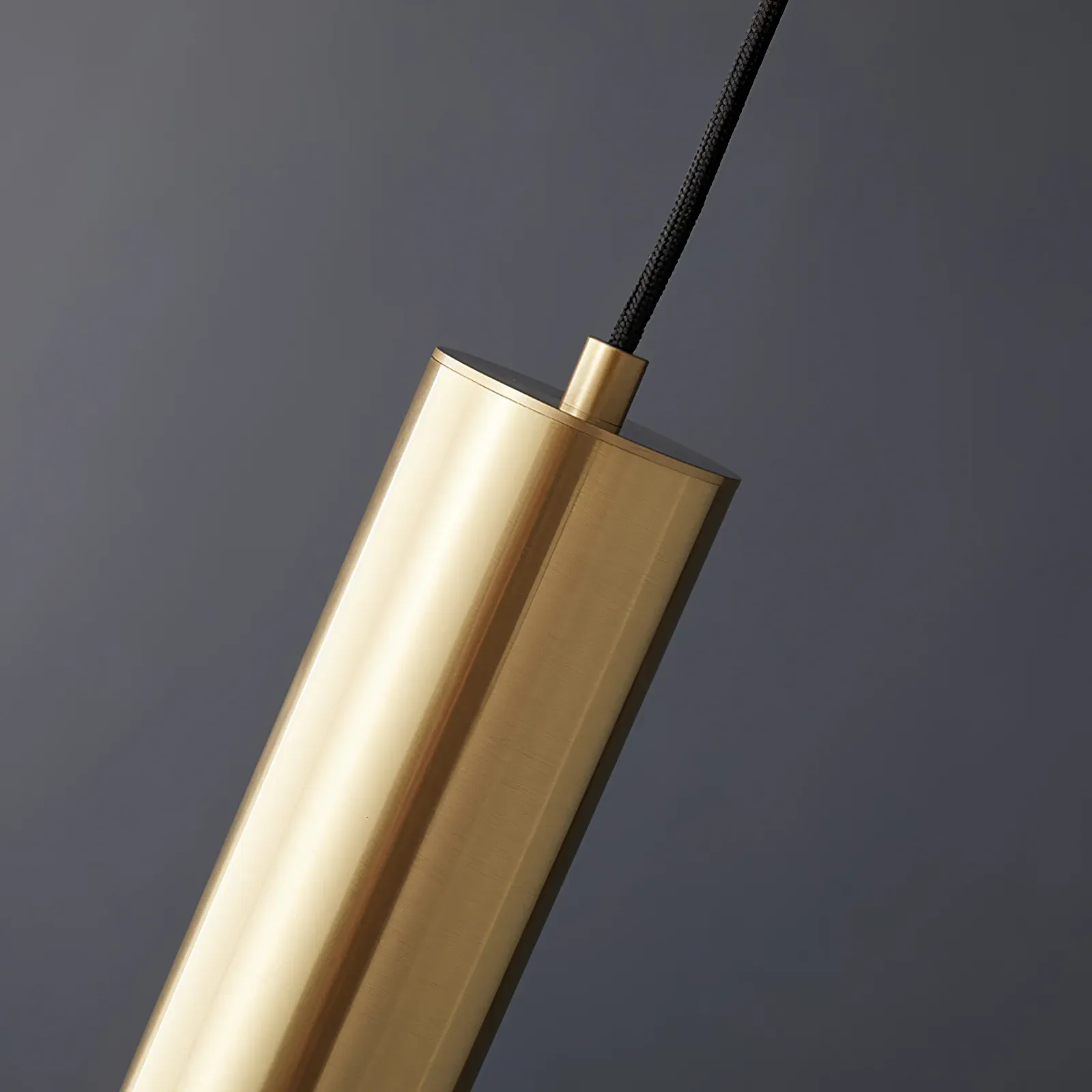 Close-up of gold cylinder pendant light fixture detail.