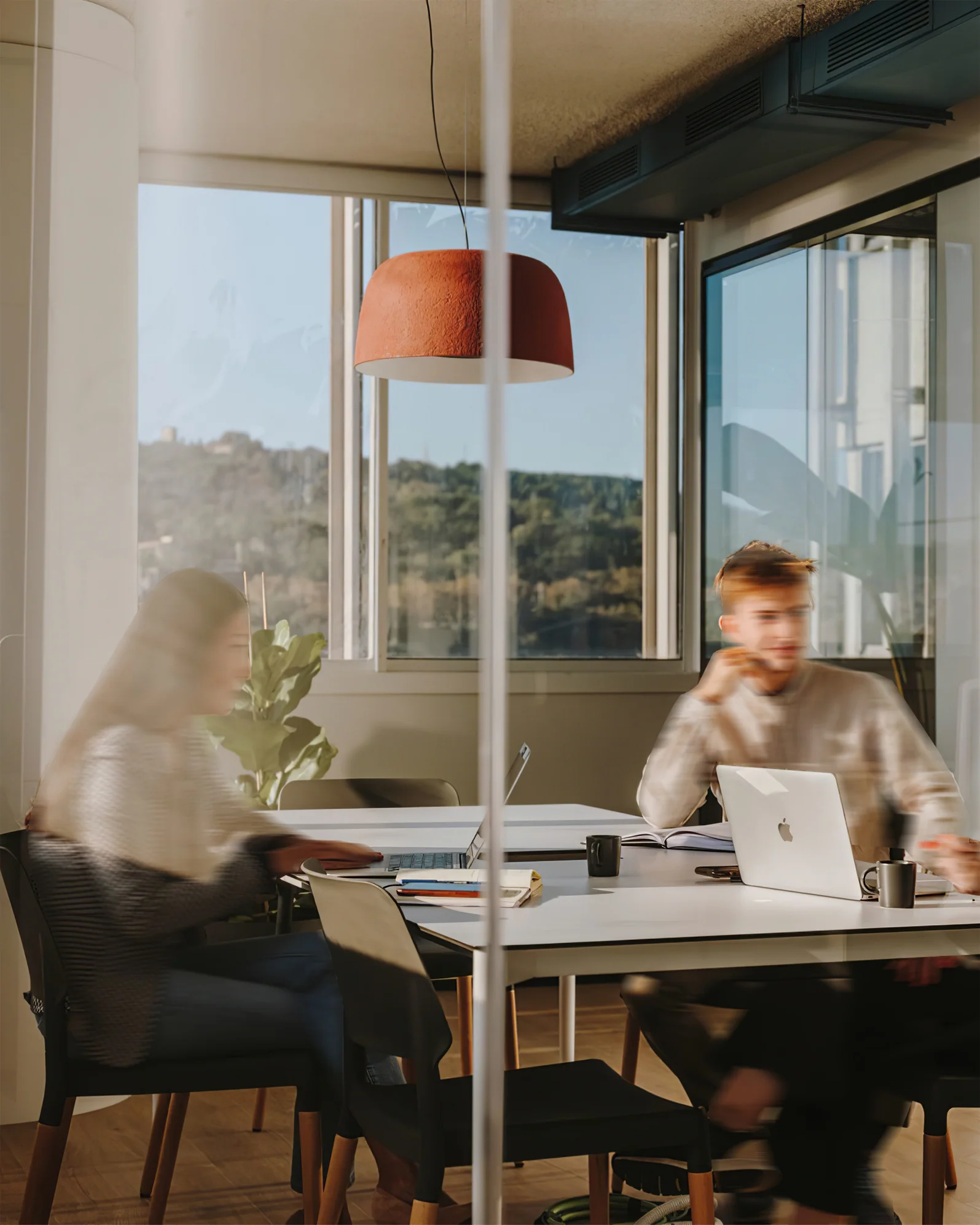 People working in a modern office with a modern round pendant light.