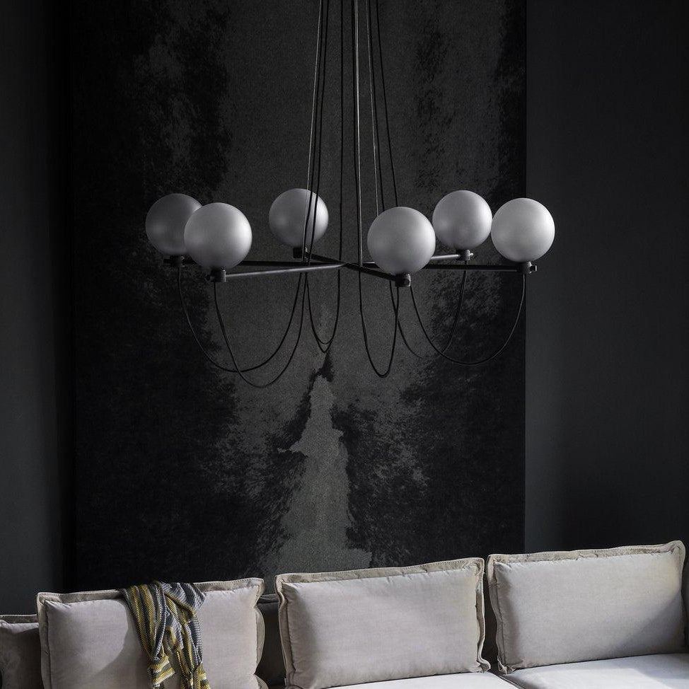 Modern glass ball chandelier over a grey couch in a living room