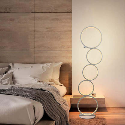 Arisha multi-ring floor lamp near bed, modern lighting.