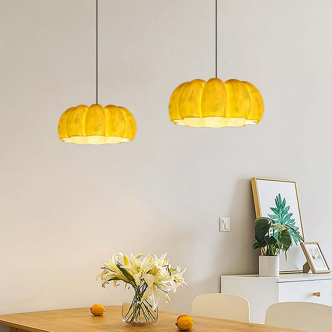 Yellow pumpkin pendant lights over dining table with flowers