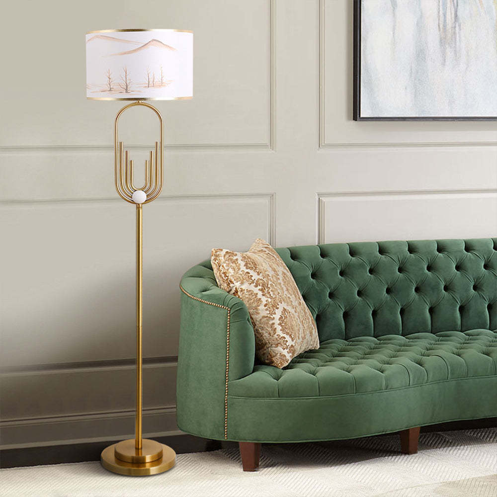 Gold Sano Floor Lamp with Landscape Shade beside green velvet sofa