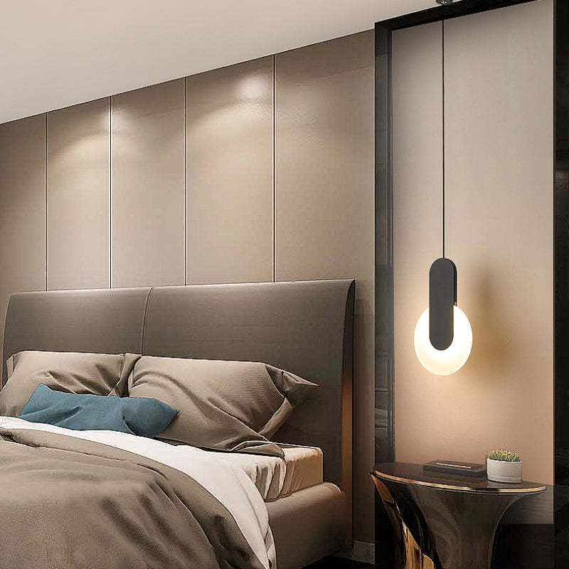 Modern minimalist LED pendant light over a bedroom bed
