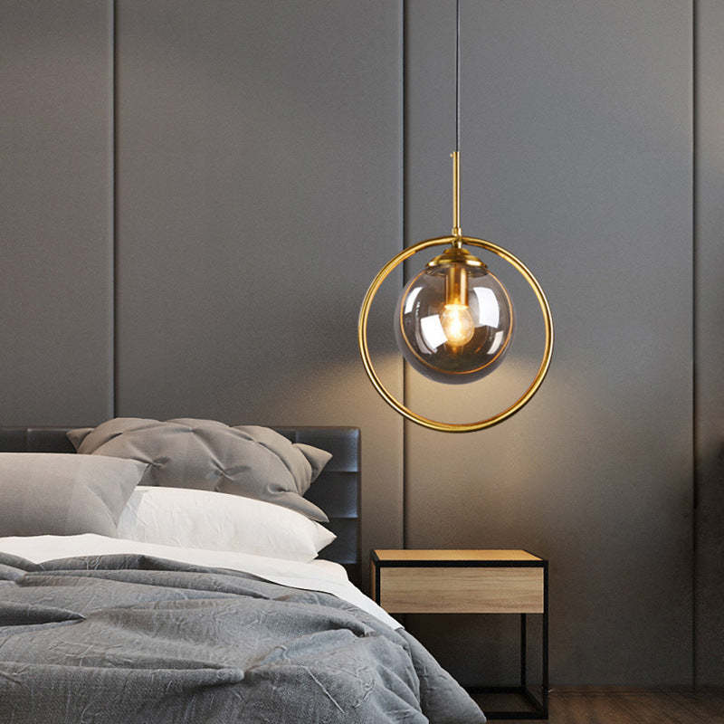 Hailie glass pendant light with gold metal ring in bedroom setting.