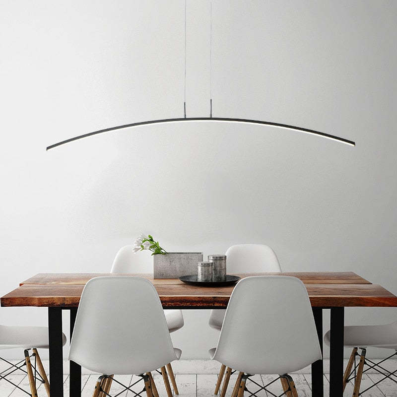 Modern curved linear pendant light above dining table.