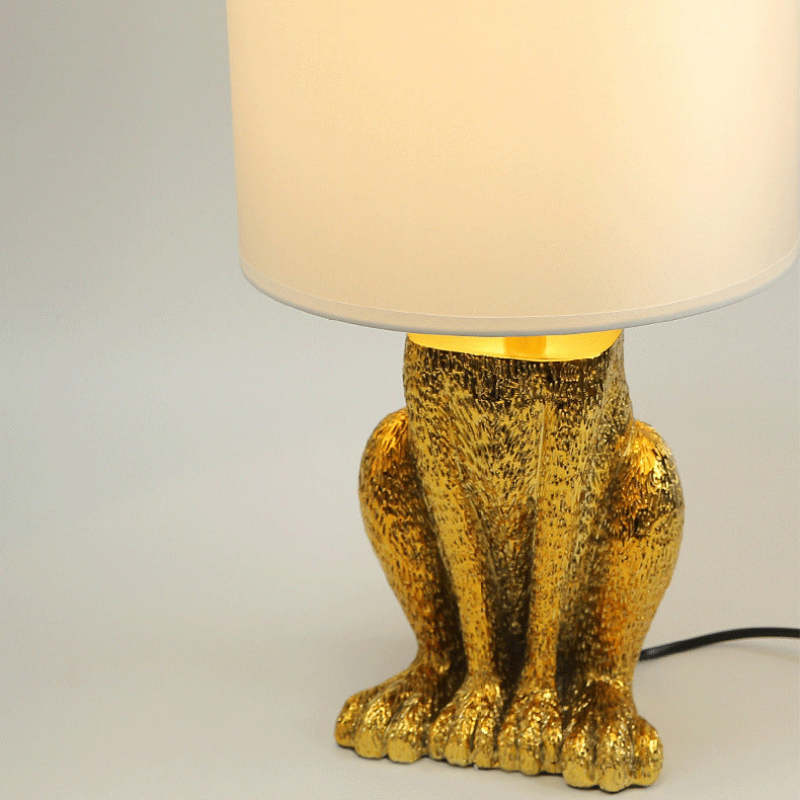 Gold rabbit table lamp with white shade.
