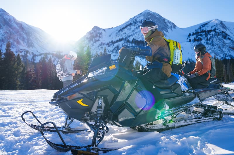 Guys in a snow motorcycle with their Turtlebox Ranger speaker in Ivory color attached to their backpack
