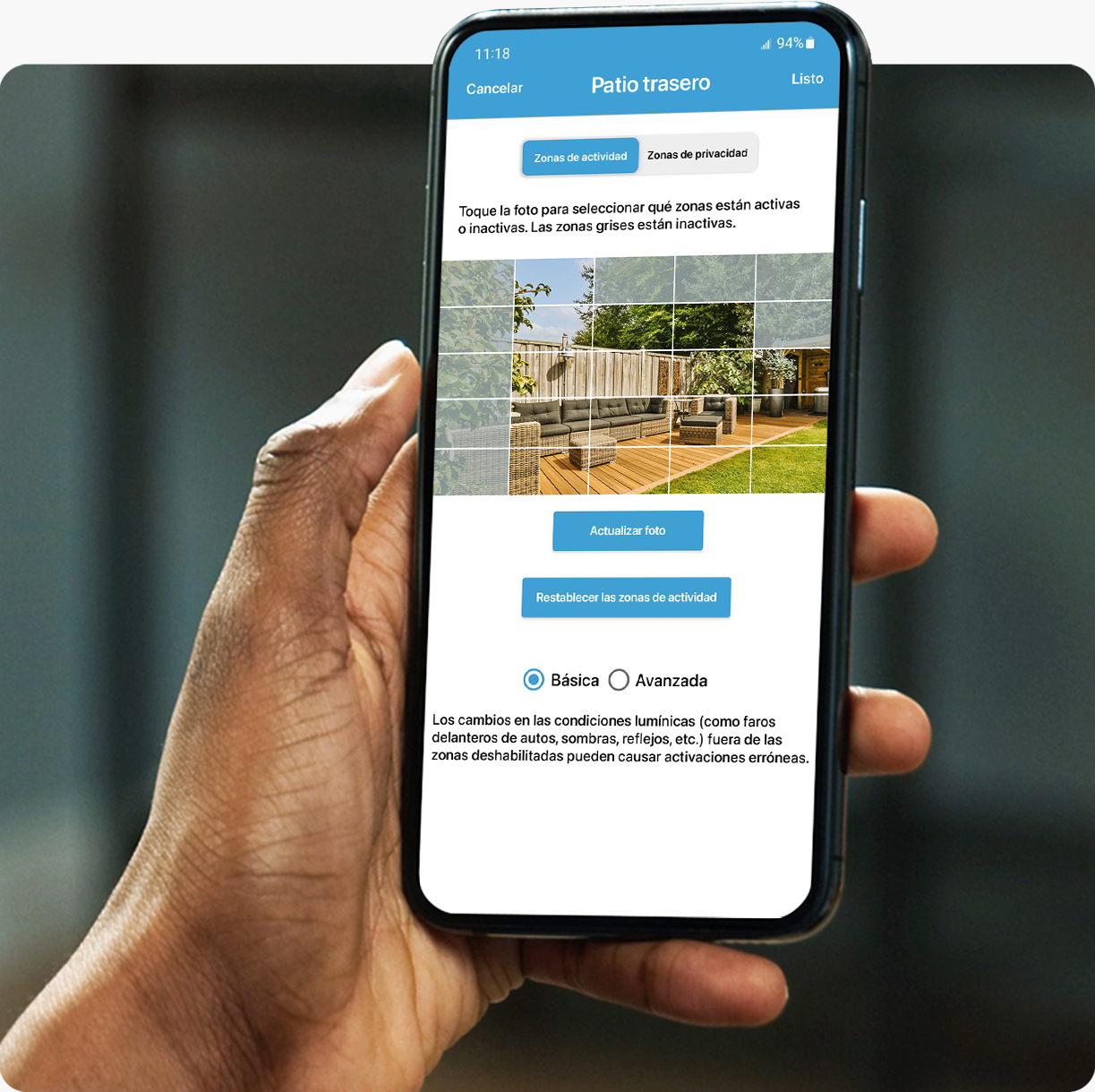 A person is holding their smartphone and using the Blink app to set up activity zones in the settings menu.