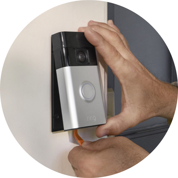 Un par de manos usan una herramienta para retirar el Timbre con cámara inalámbrico Ring de un soporte de pared.