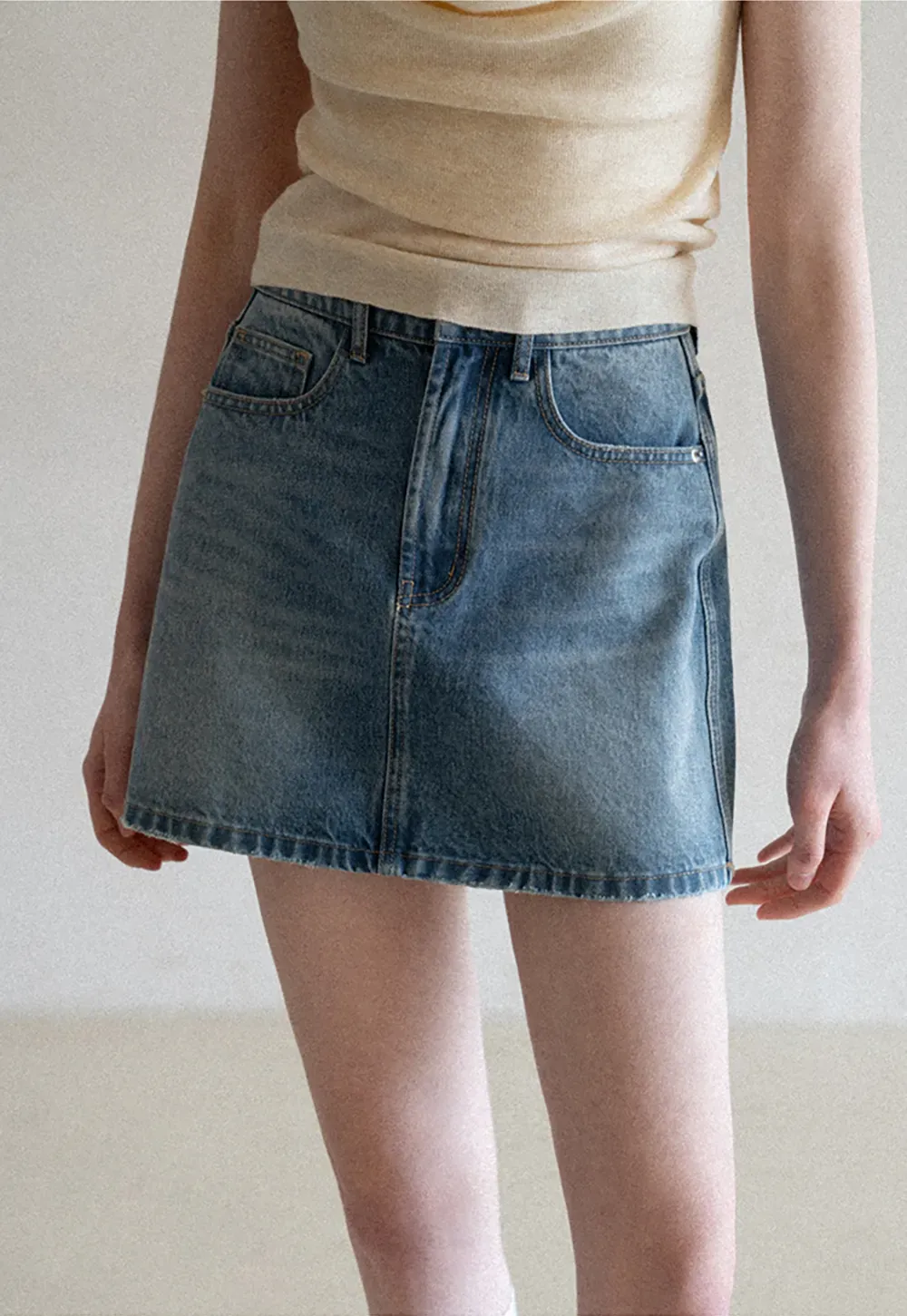 Denim mini skirt with frayed hem and front pockets