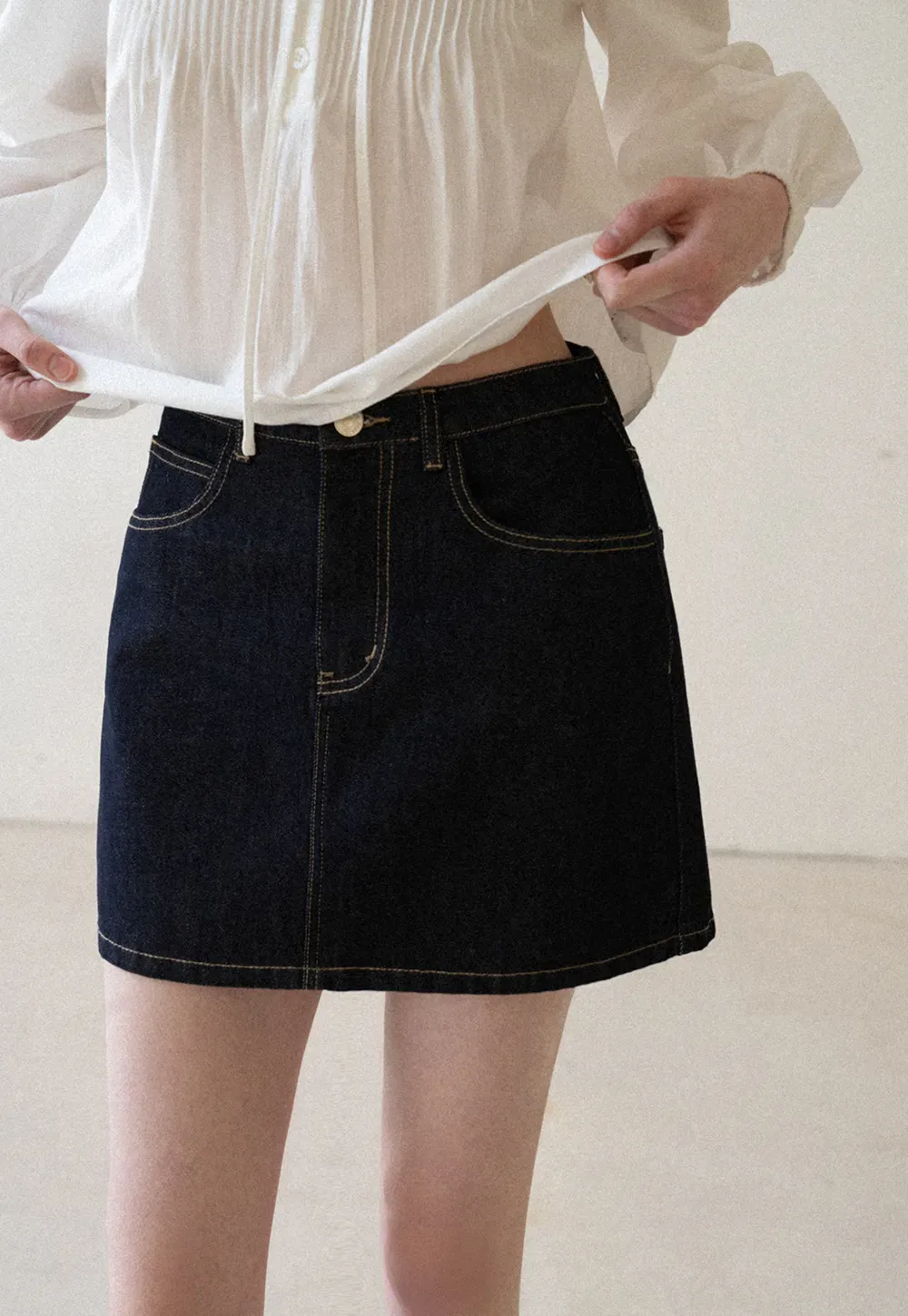 A-line denim skirt with front pocket design and adjustable waistband.