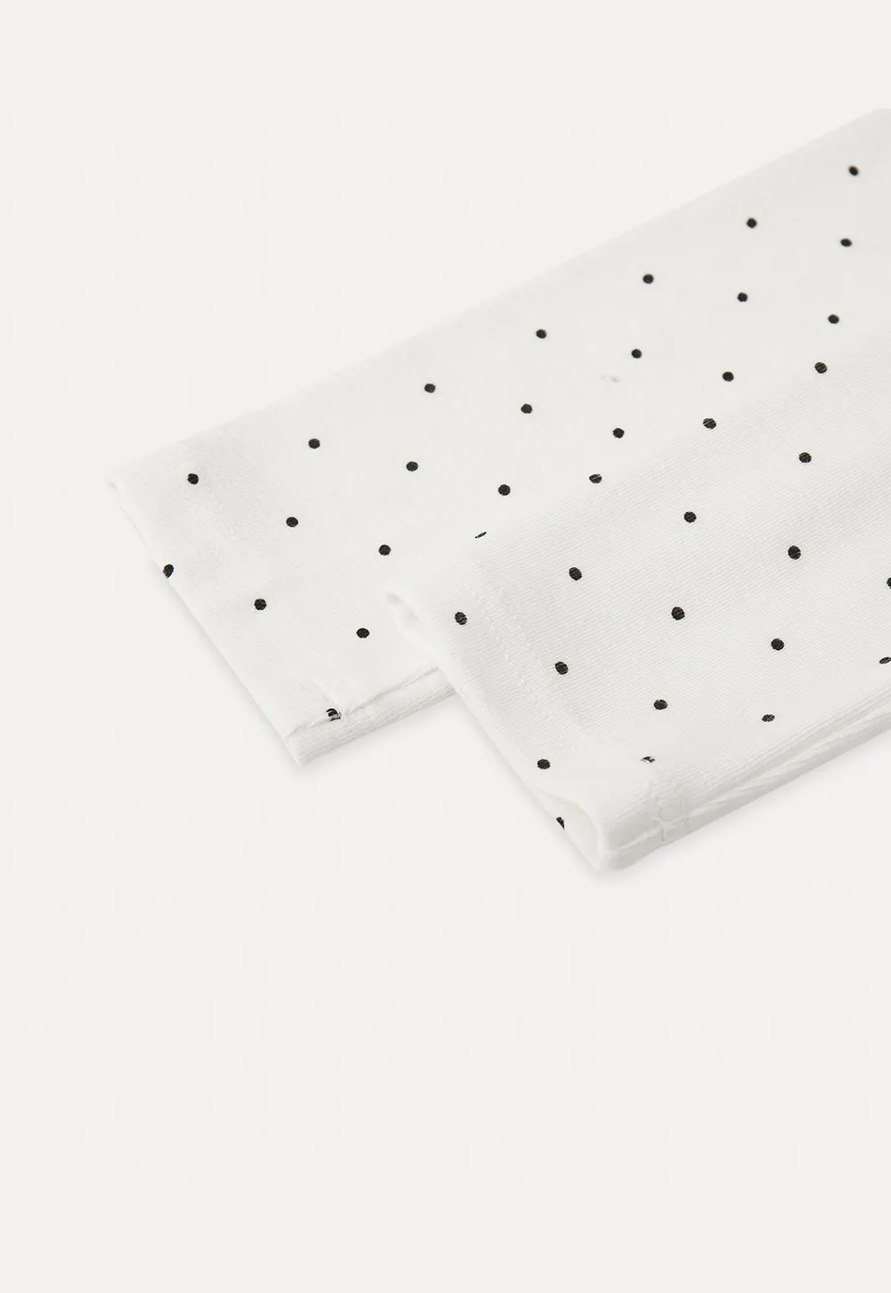 Elegant sleeveless dress with collar layered over polka dot top