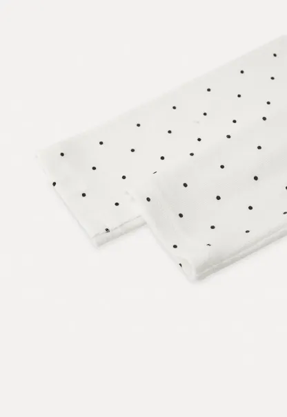 Elegant sleeveless dress with collar layered over polka dot top