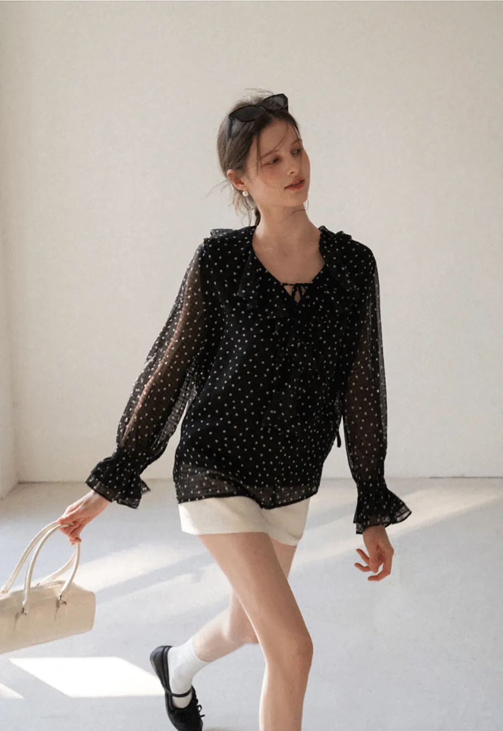 Sheer polka dot blouse with ruffled neckline and long sleeves