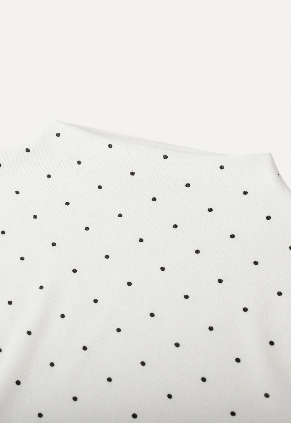 Elegant sleeveless dress with collar layered over polka dot top