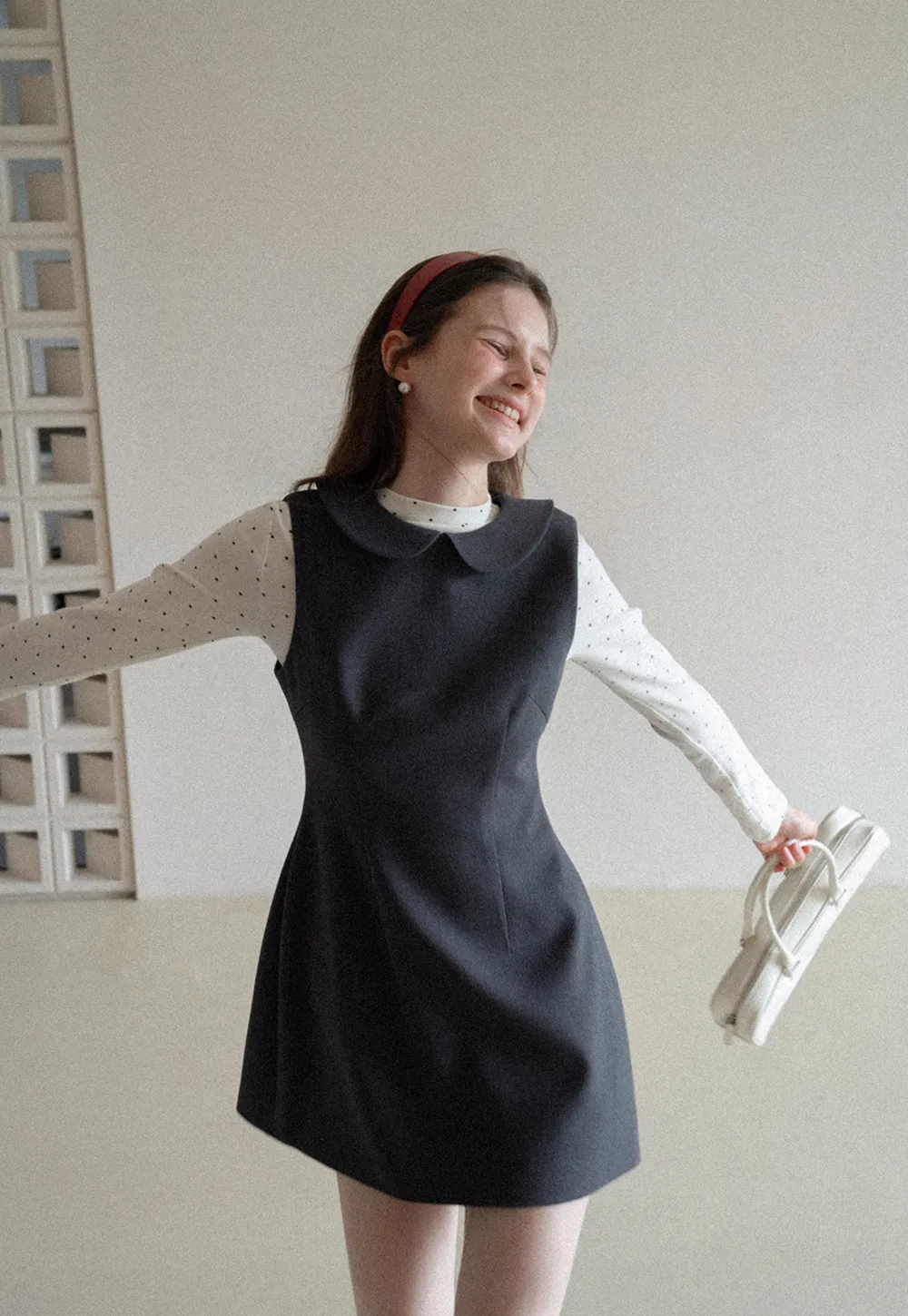 Elegant sleeveless dress with collar layered over polka dot top