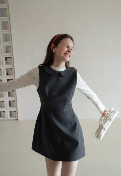 Elegant sleeveless dress with collar layered over polka dot top